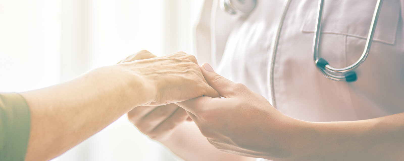 Close up image of a doctor holding the hand of her patient as a method of comfort after being diagnosed with asbestos-related cancer.