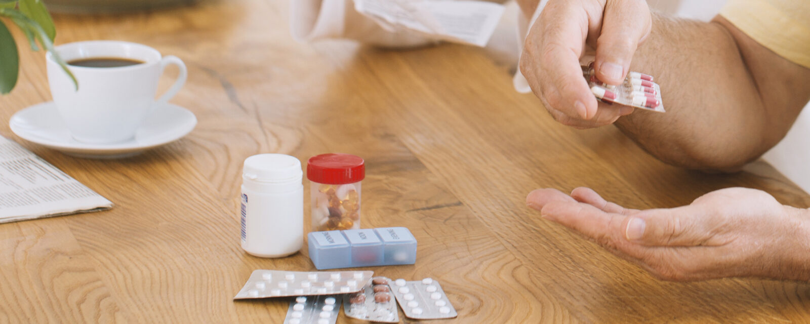 Image of a patient sitting down sorting through chemotherapy medications on a wooden table.