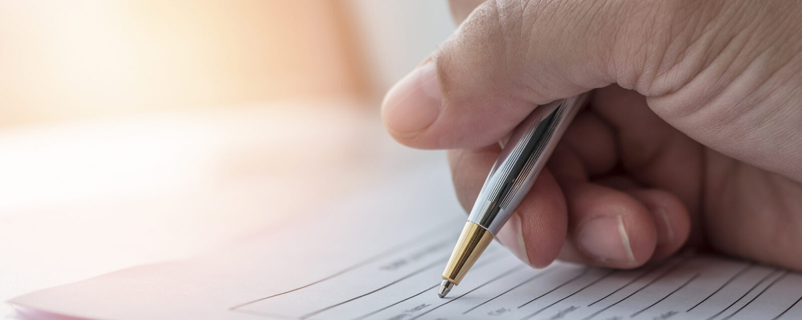 Hand filling out mesothelioma claim forms with a pen on legal documents