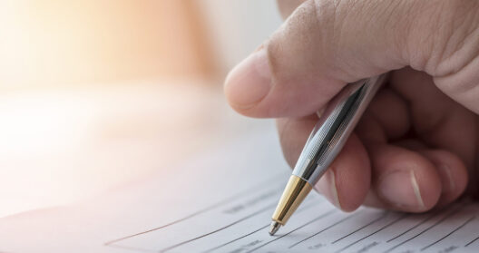 Hand filling out mesothelioma claim forms with a pen on legal documents