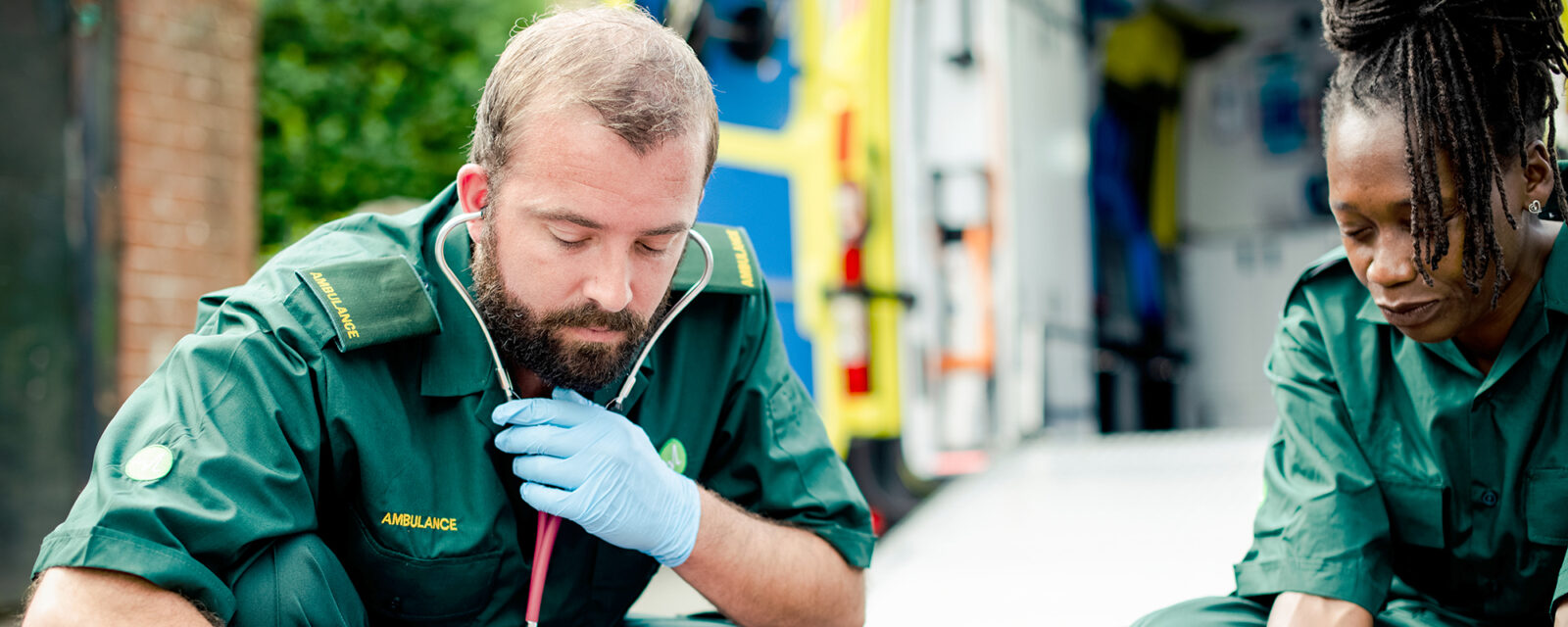 Image of two first responders in green, potentially being exposed to asbestos on the job.