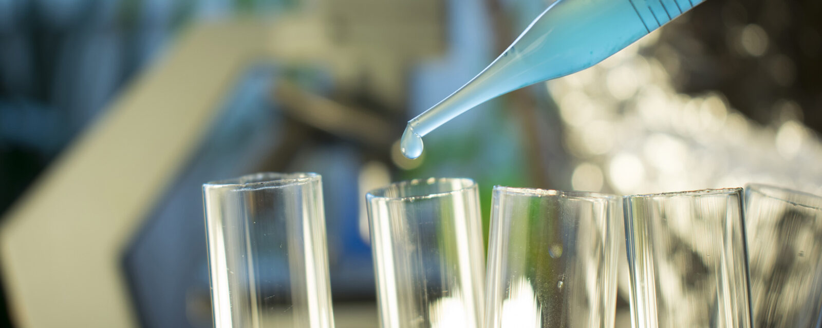 Close-up image of a pipette dropping chemotherapy treatment into test tubes.
