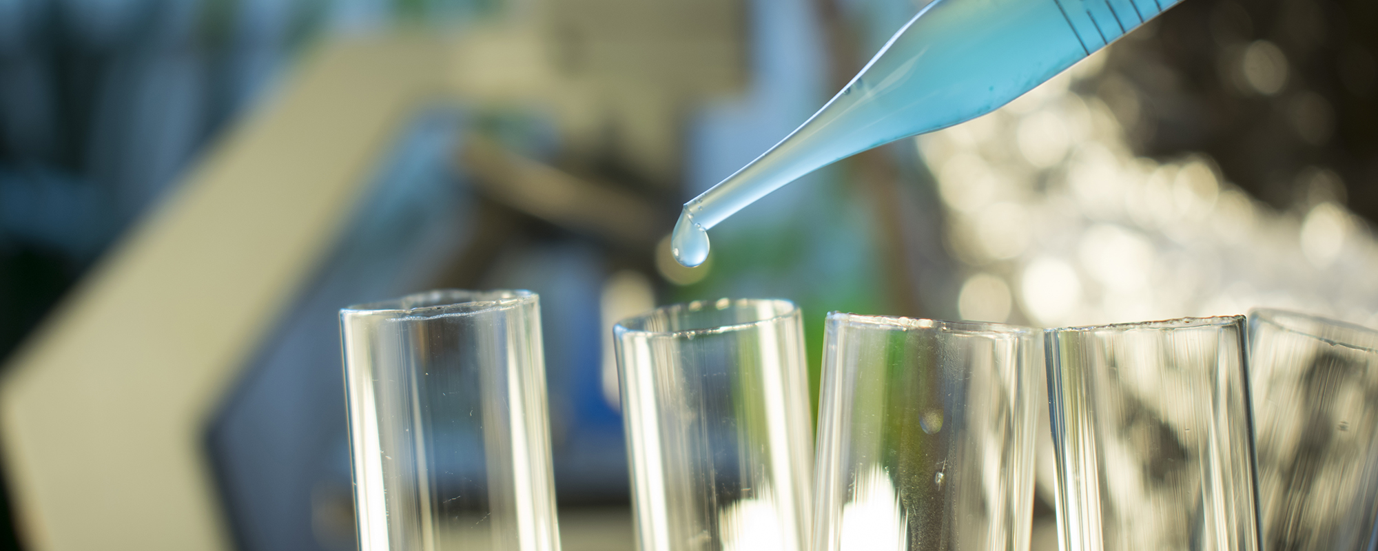 Close-up image of a pipette dropping chemotherapy treatment into test tubes.