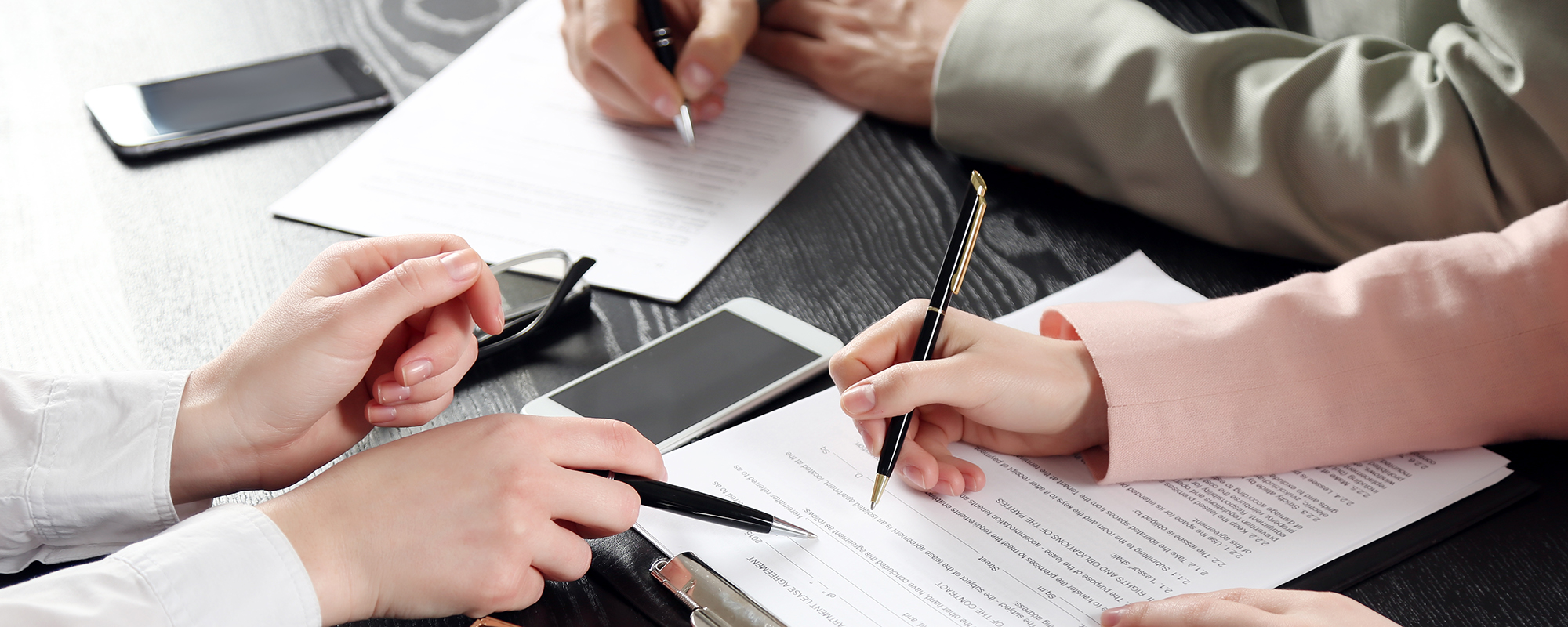 Close up image of a legal team working on paperwork together.