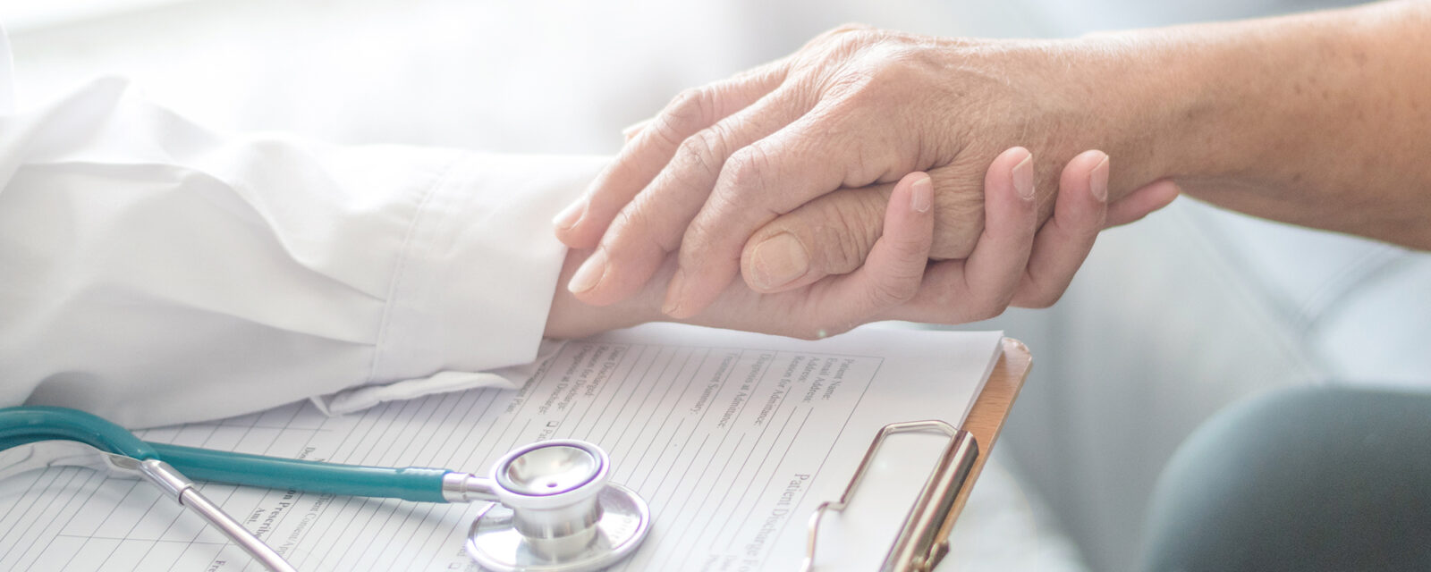 Close up image of a doctor holding the hand of her patient as a method of comfort.