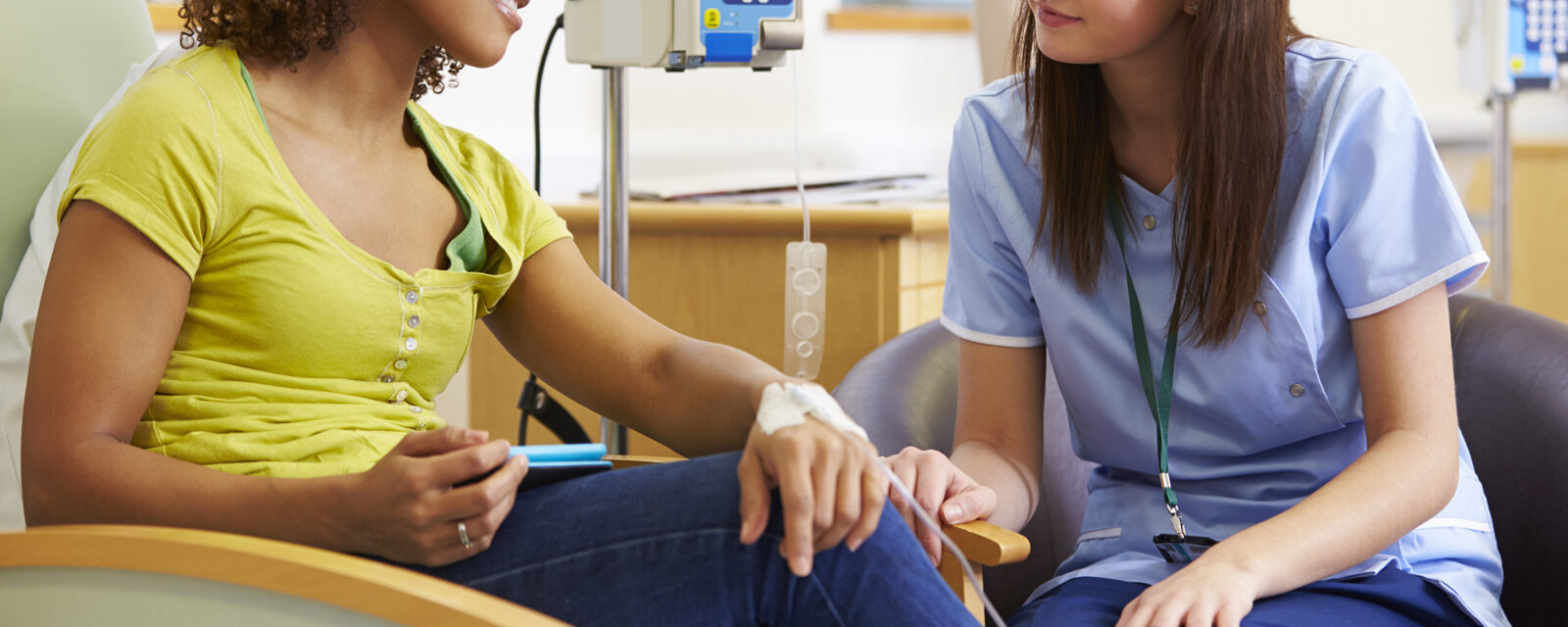 Woman in yellow shirt talking with female physician.