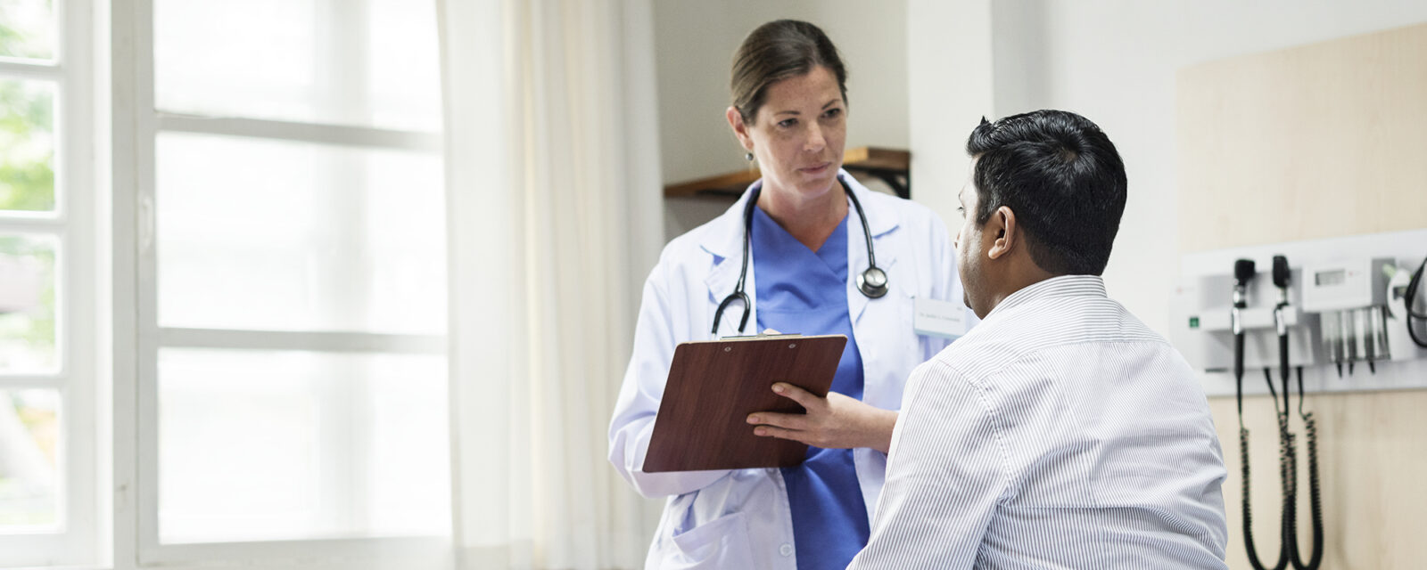 Image of a doctor holding a clip board and looking at her patient.