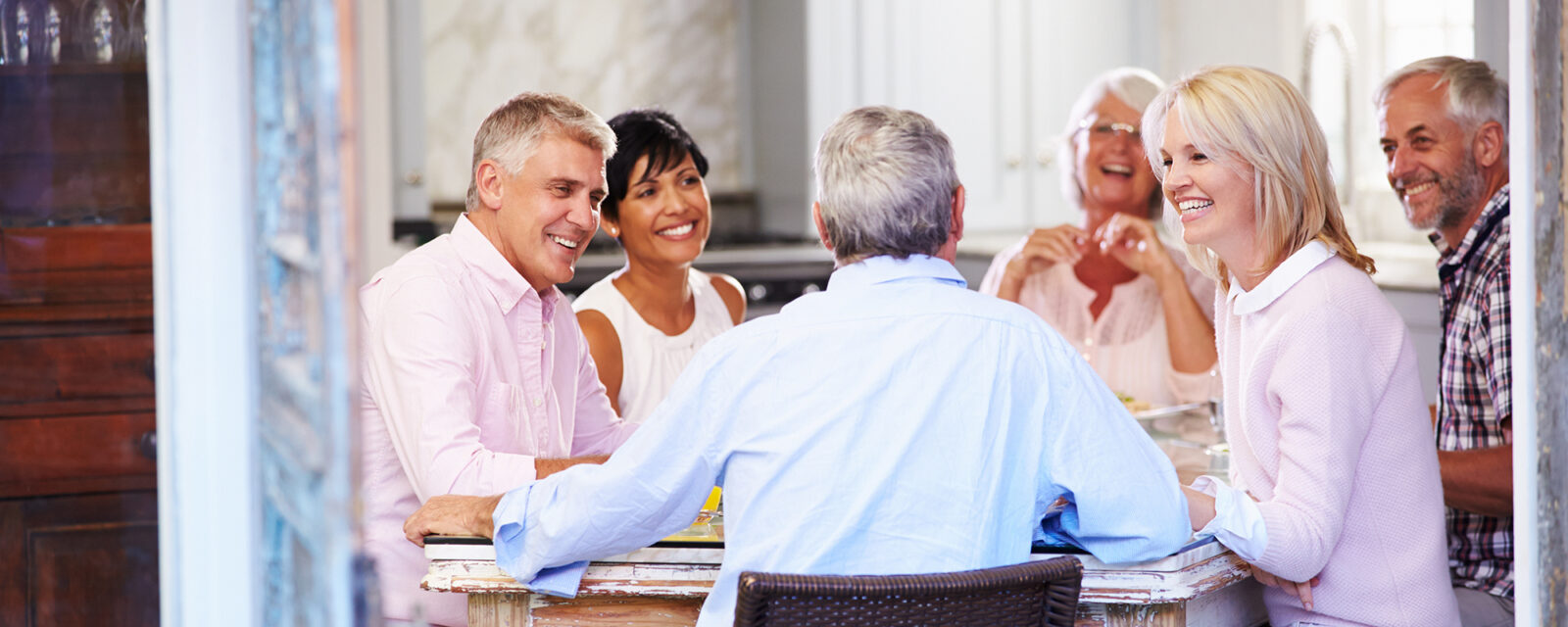A group of seniors sitting around a table and smiling at each other.
