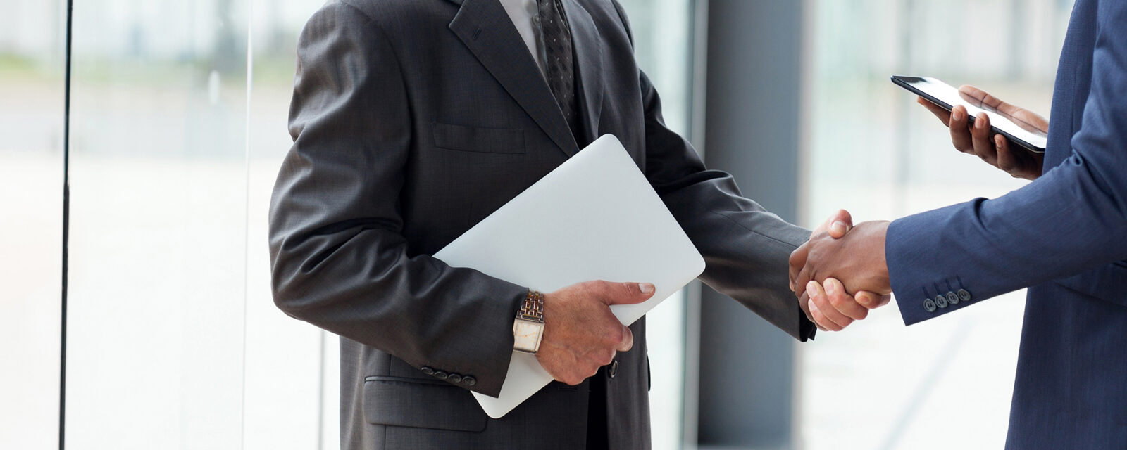 Image of a handshake between two legal professionals. One is in a black suit, the other in blue.