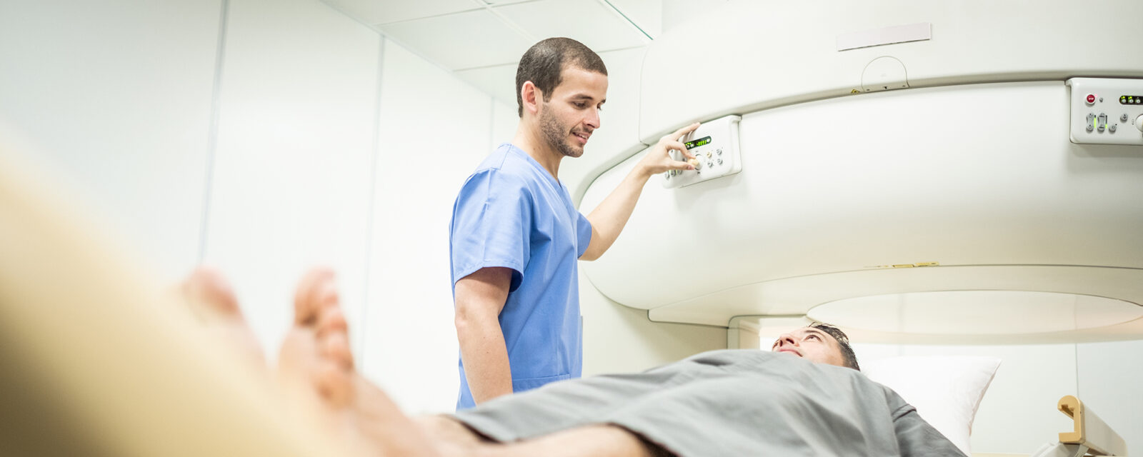 Image of a technician operating a machine that will be used to scan a patient lying on the table for mesothelioma.