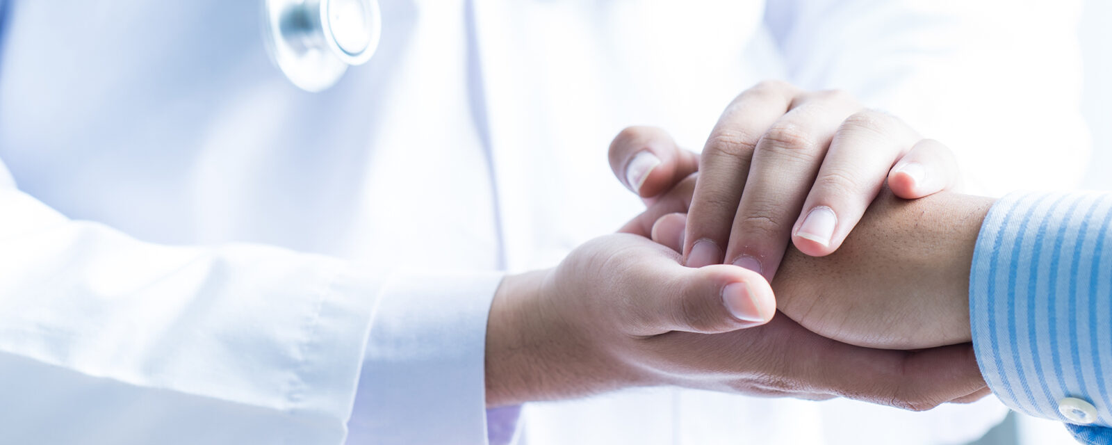 Close up image of a doctor holding their patient's hand as a method of comfort after explaining the effects of stage 4 mesothelioma.
