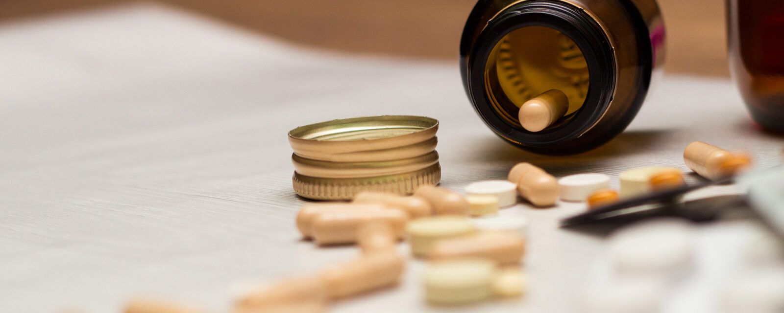 Floor view image of a bottle of pills that has fallen over and spilled.