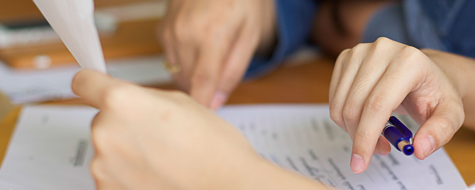 Close up image of two people's hands as they are going over documents.