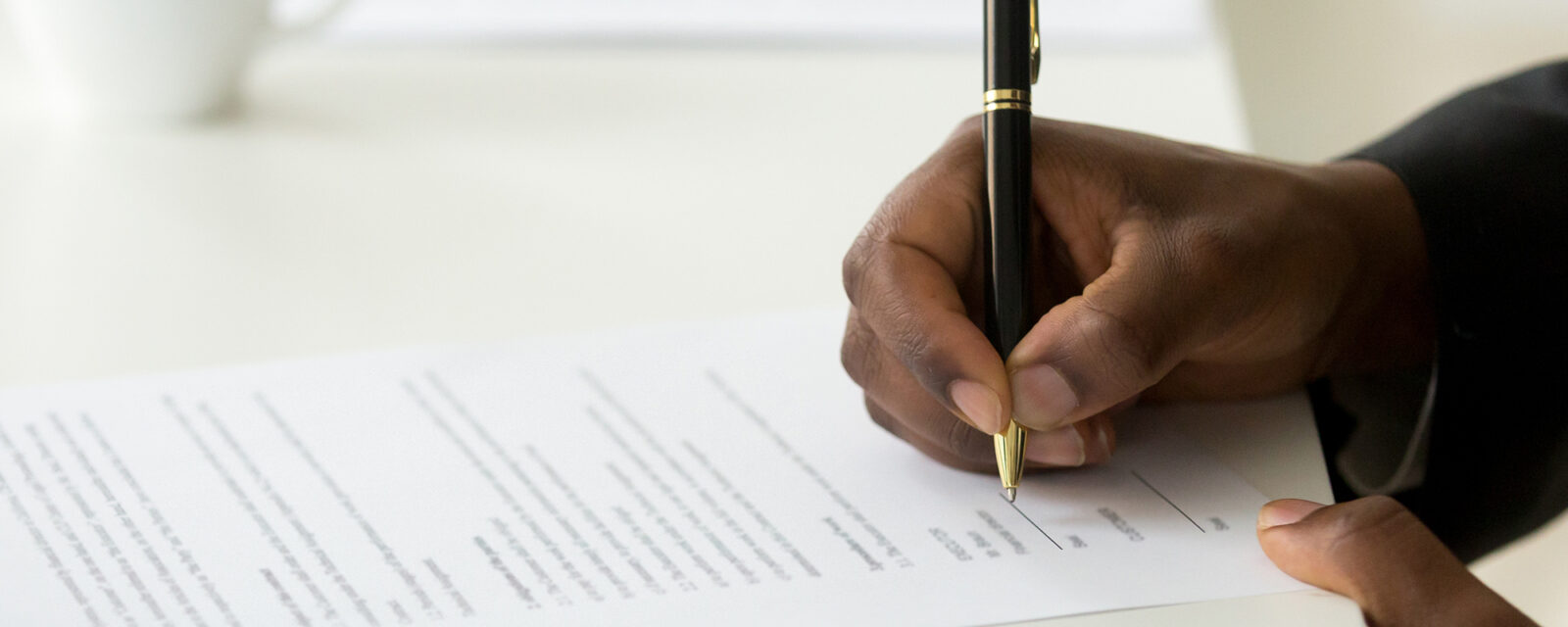 Close up image of someone signing a legal document.