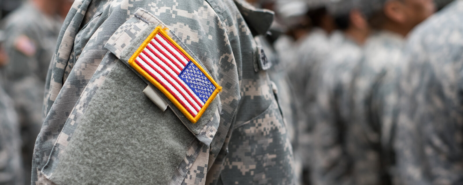 Close up image of a veteran's shoulder. They are in uniform and there is a clear view of a patch with the American flag on it.