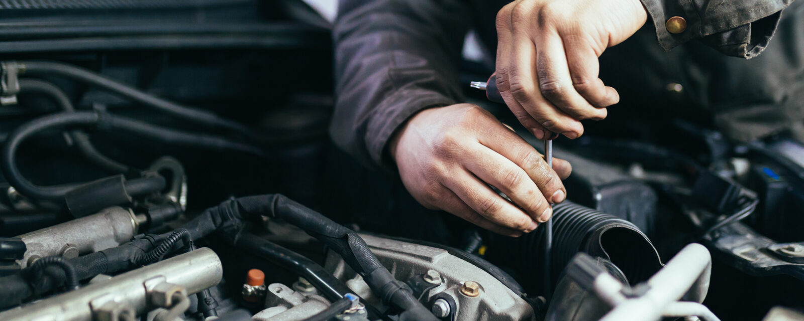 Close-up image of a mechanic working on a vehicle, an occupation that is at high risk for asbestos exposure.
