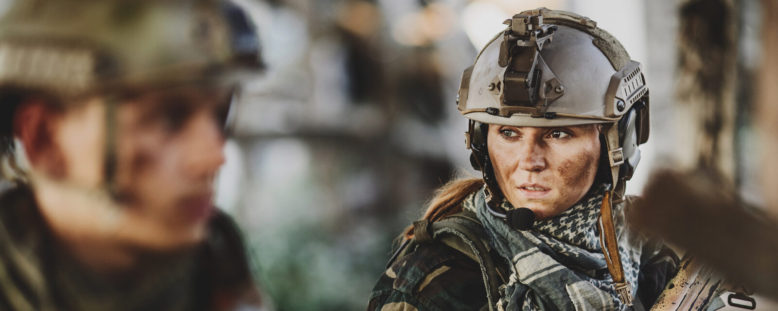 This is an image of a female service member in gear and looking off into the distance.
