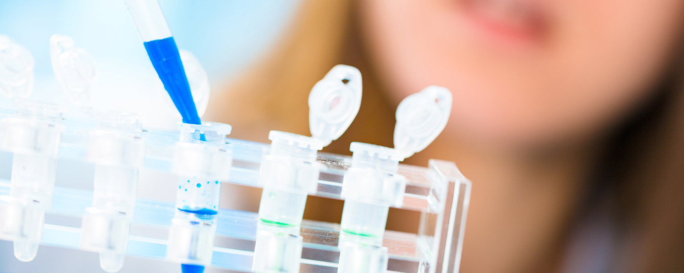 Image of a female lab tech using a droplet to add a substance into test tubes.