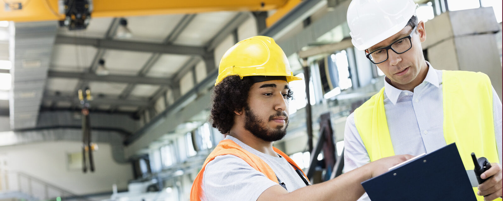 Two men discussing construction projects wearing hard hats and high-visibility vests.