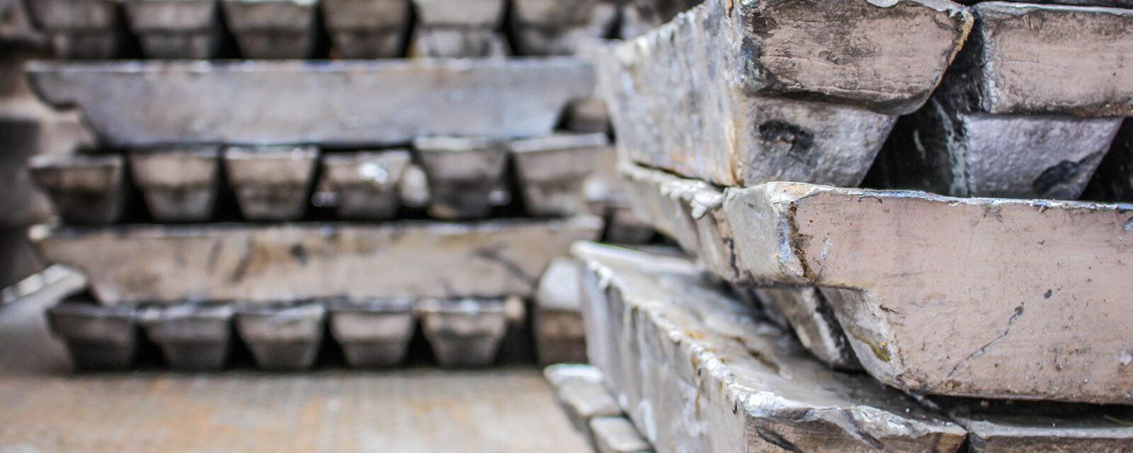 Close up view of lead ingots with more lead ingots in the background.