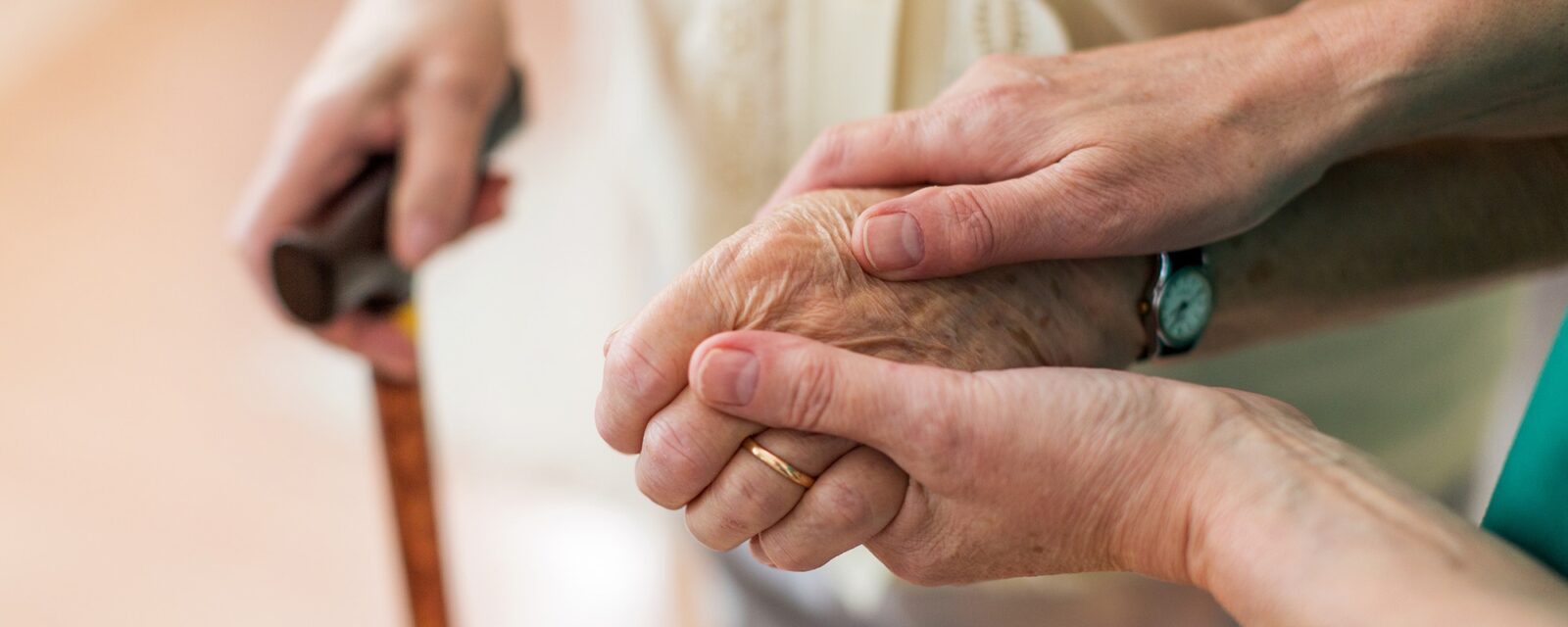 Nurse consoling her elderly patient by holding her hands.