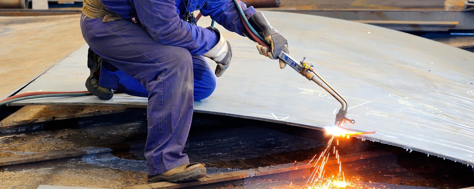 A steelworker working at the shop and welding a piece of metal.