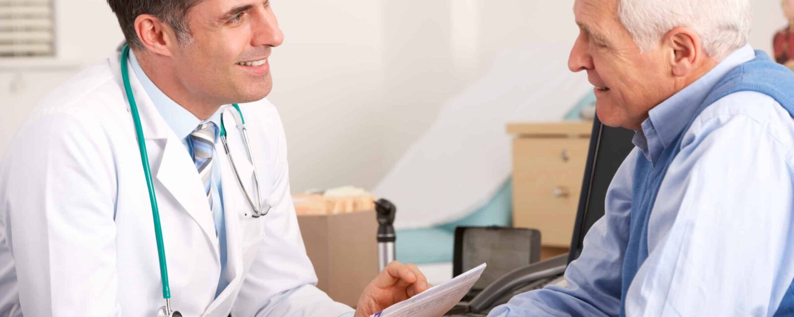 Senior man talks with his doctor over medical paperwork.