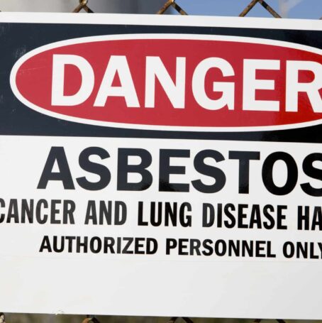 Danger asbestos warning sign on chain-link fence.