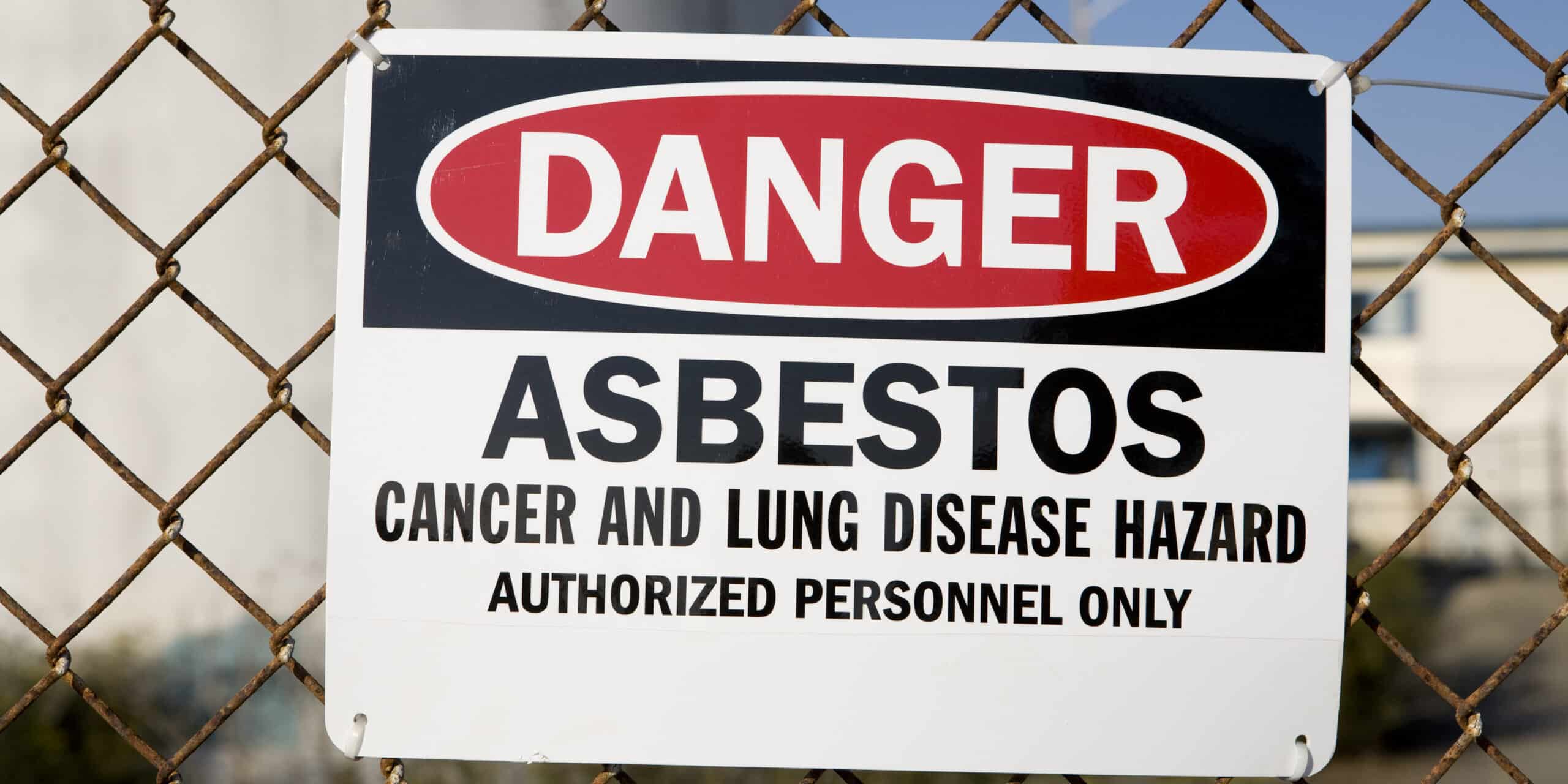 Danger asbestos warning sign on chain-link fence.