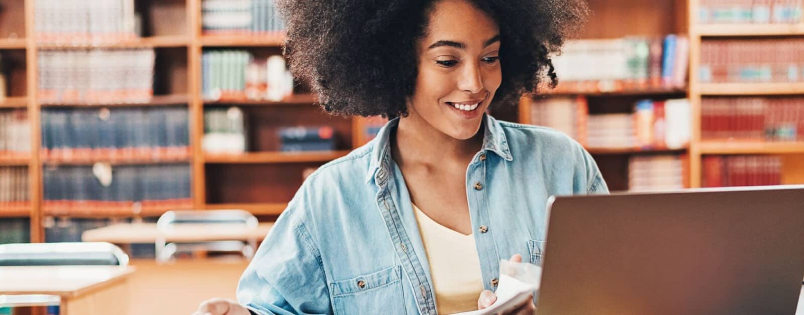 Student in a library on laptop.
