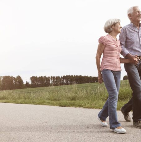 Photo of older couple walking together outdoors.