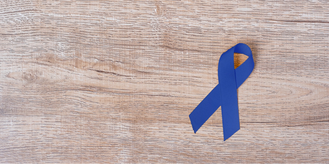 Image of blue ribbon lying on wooden desk.