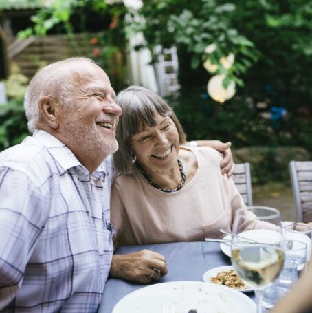 Elderly couple smiling while having a meal with group.