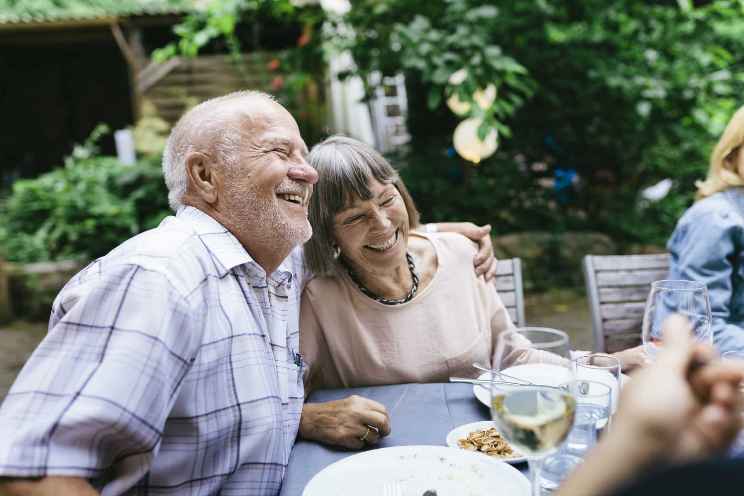 Elderly couple smiling while having a meal with group.