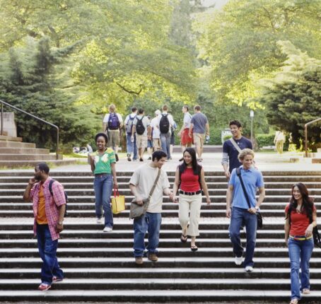 Students walking down campus steps with trees in the background.