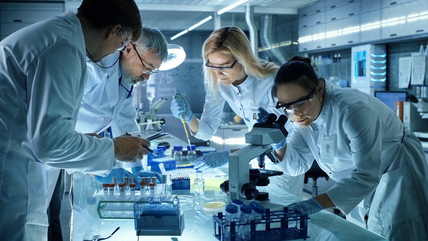 Image of mesothelioma doctors working in lab with microscopes, test tubes, and personal protective equipment.
