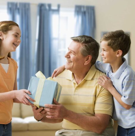 Man in yellow shirt holding gift box given to him by his two children