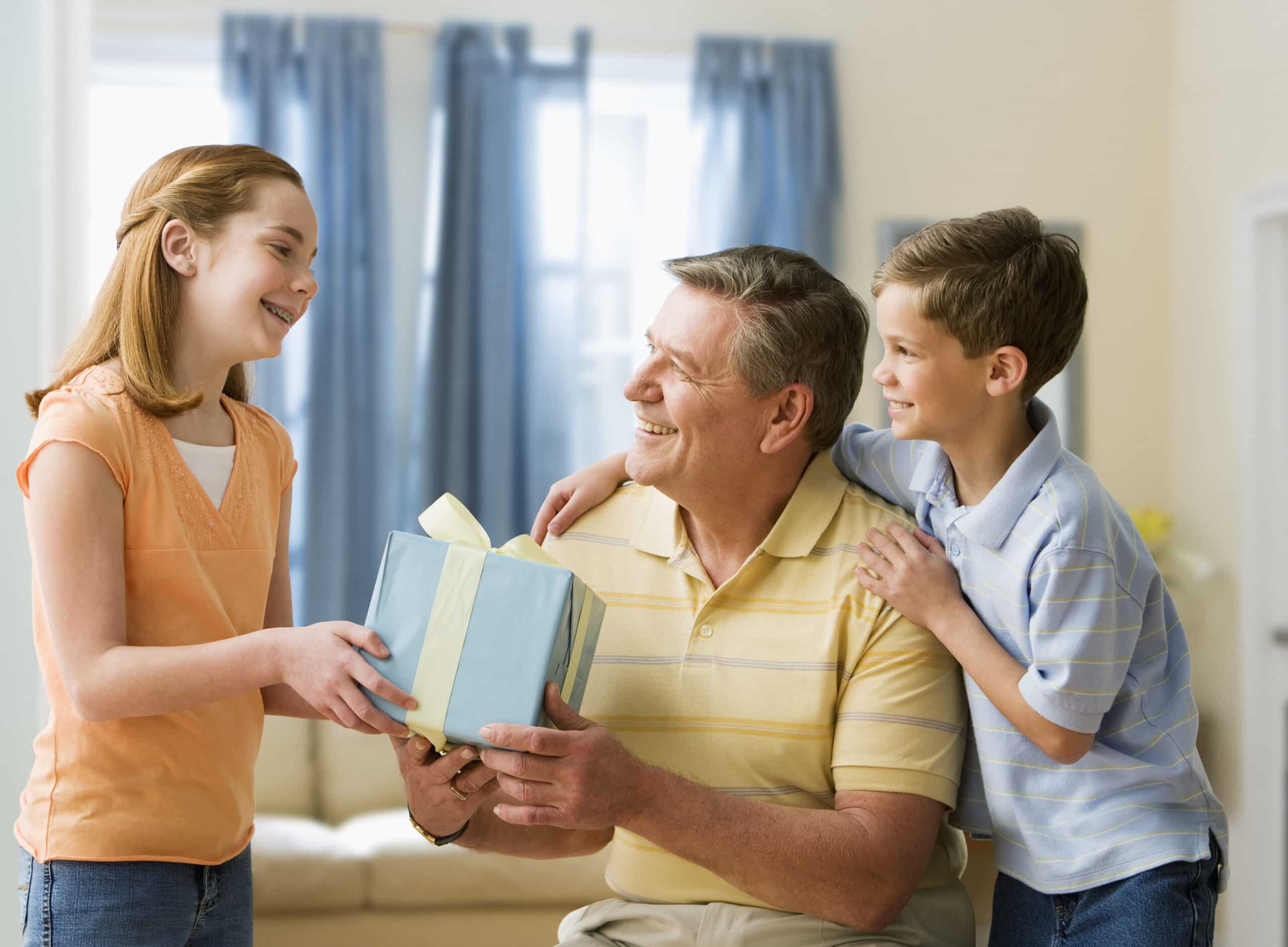 Man in yellow shirt holding gift box given to him by his two children