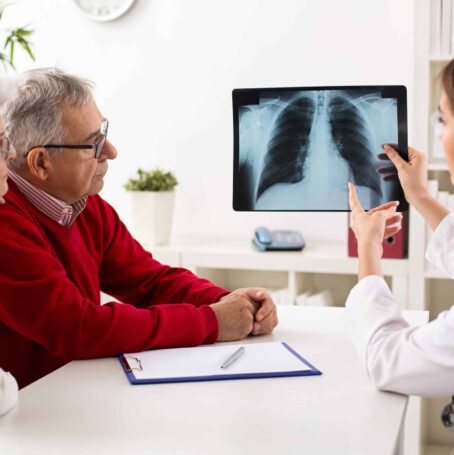 Doctor showing senior patient an x-ray of the lungs that models the long-term effects of smoking cigarettes.