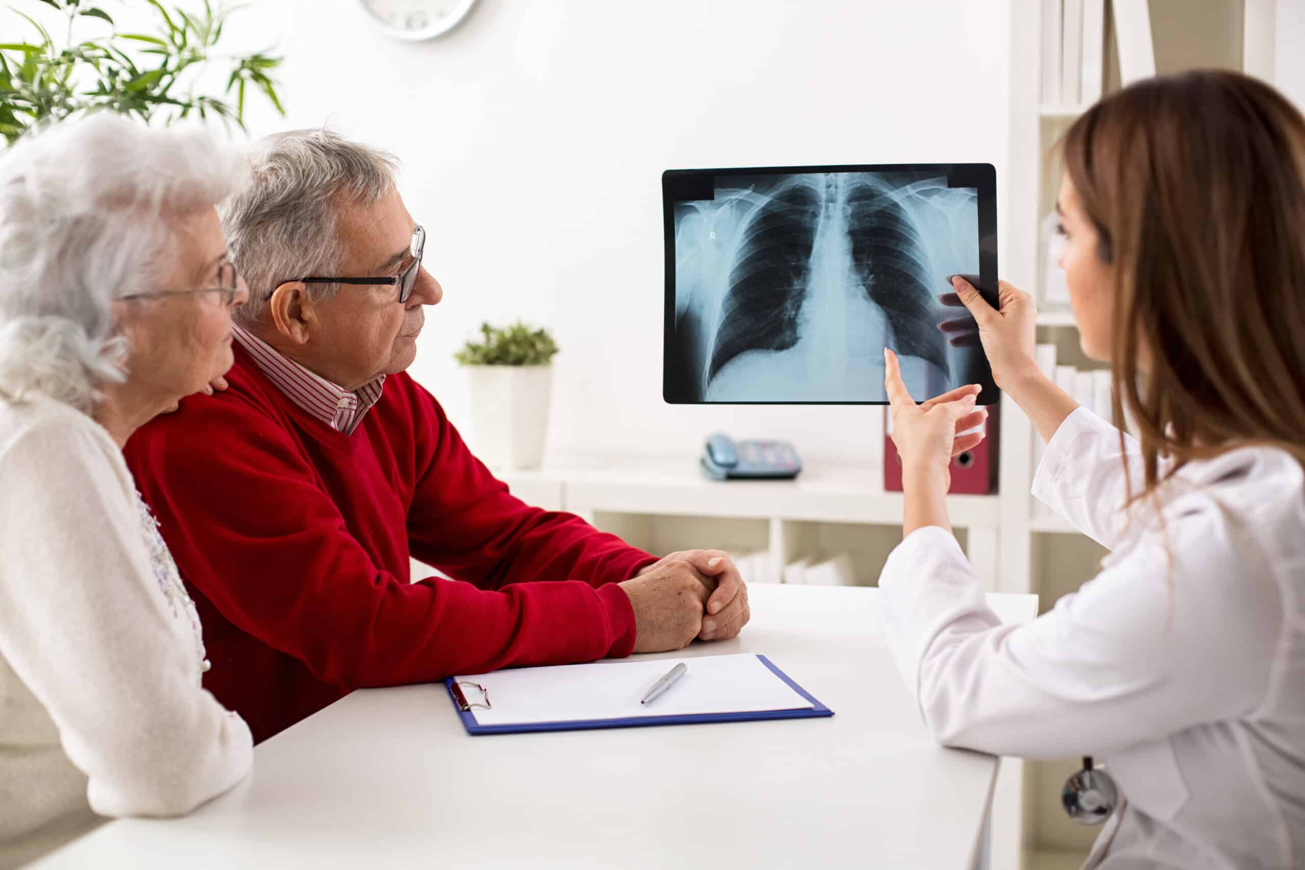 Doctor showing senior patient an x-ray of the lungs that models the long-term effects of smoking cigarettes.