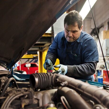 Male auto mechanic working on car in shop exposed to asbestos