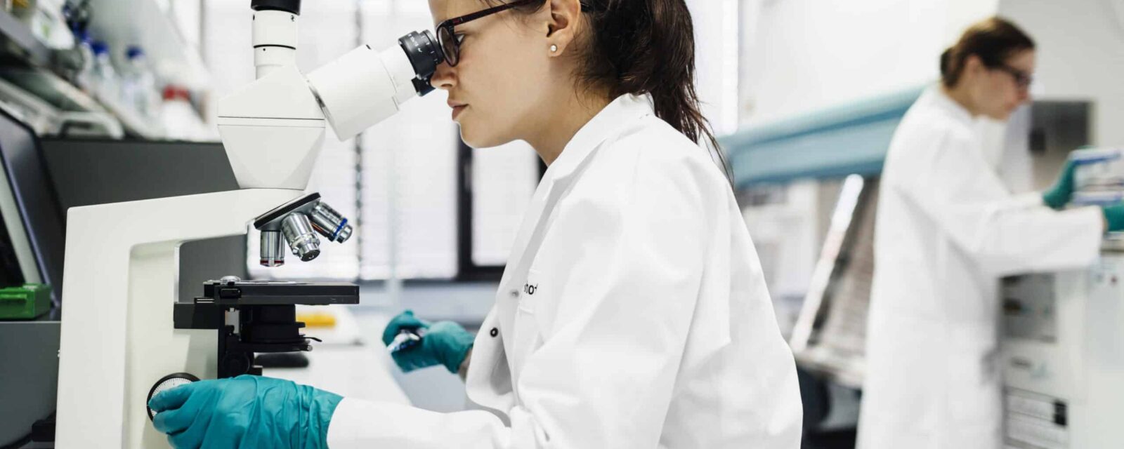 This is an image of a mesothelioma researcher looking through a microscope in a lab.