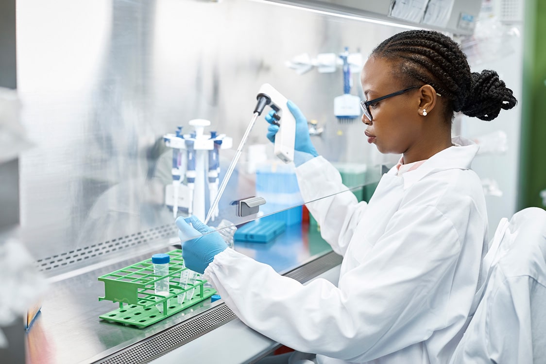 Female scientist analyzing medical sample in test tube. Young researcher is wearing lab coat.