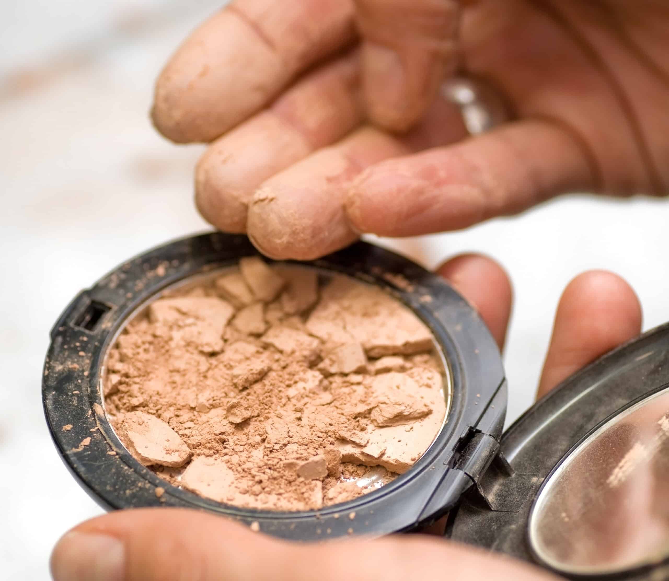 A shattered cosmetic product and a person's fingers touching the item. MoCRA law adds more guidelines and restrictions to cosmetics products.