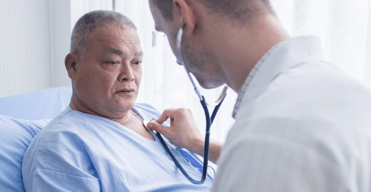 Young male doctor using stethoscope to listen to heartbeat of old male patient.