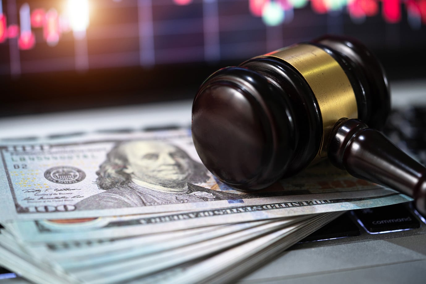 Close up of gavel laying on top of hundred-dollar bills.