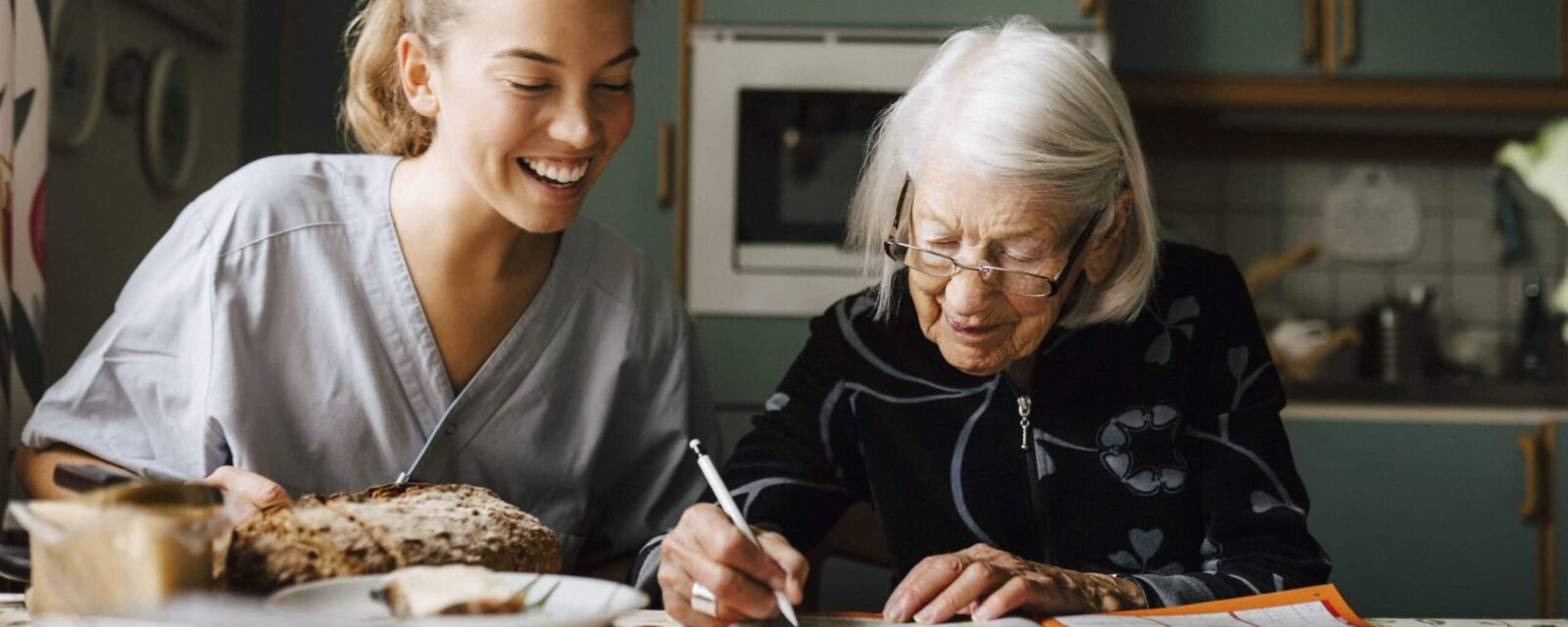 Elderly woman sitting with emotional support caregiver.