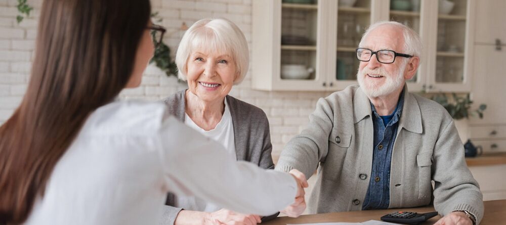 Man shaking hands with woman at table while reviewing mesothelioma legal compensation documents