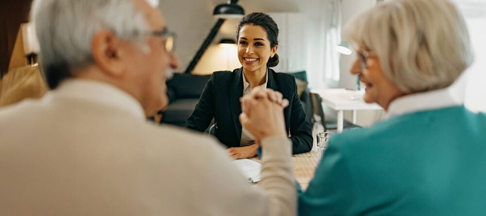 Man and woman holding hands while speaking with a female mesothelioma legal advisor.