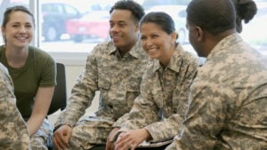 Military men and women sitting in a group and smiling at each other.